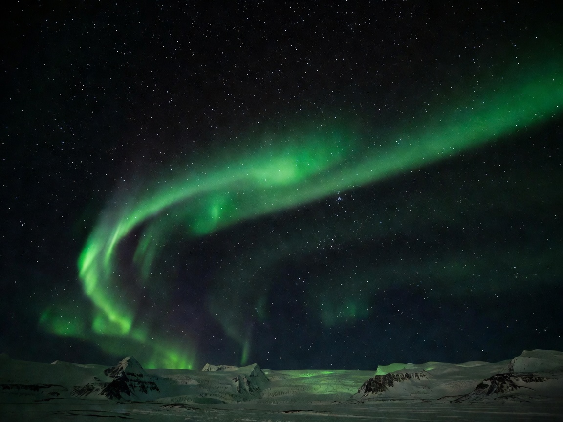 Emerald green ribbon of aurora borealis curving across an inky starry Arctic sky